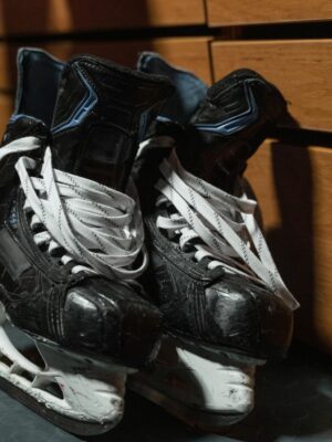 A pair of used ice hockey skates lie on the floor in a locker room, showcasing sports equipment.