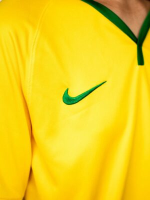 Crop unrecognizable person in bright yellow shirt standing near white stairway for training in sports hall