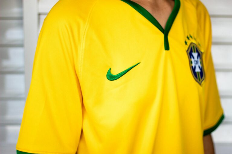Crop unrecognizable person in bright yellow shirt standing near white stairway for training in sports hall