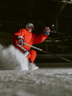 Ice hockey player performing a powerful move on an indoor rink, showcasing skill and speed.