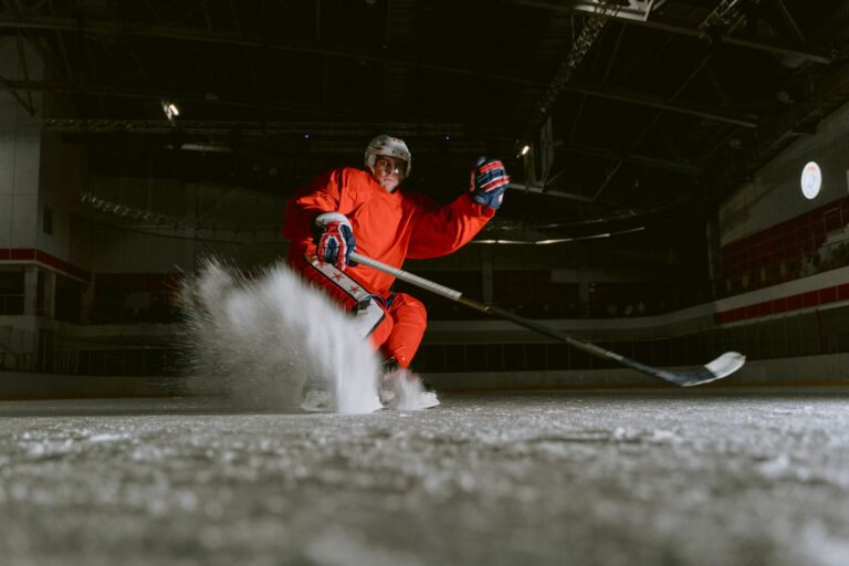 Ice hockey player performing a powerful move on an indoor rink, showcasing skill and speed.